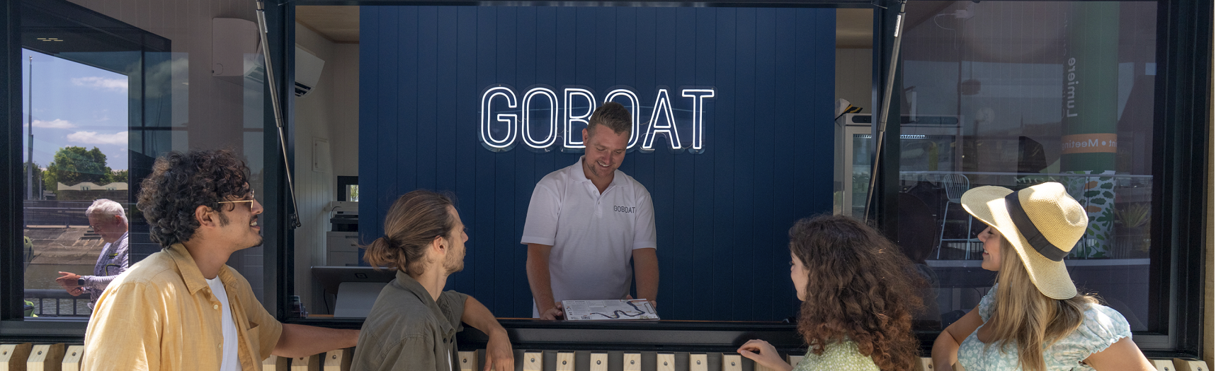 Man standing in front of GOBOAT sign talking to customers