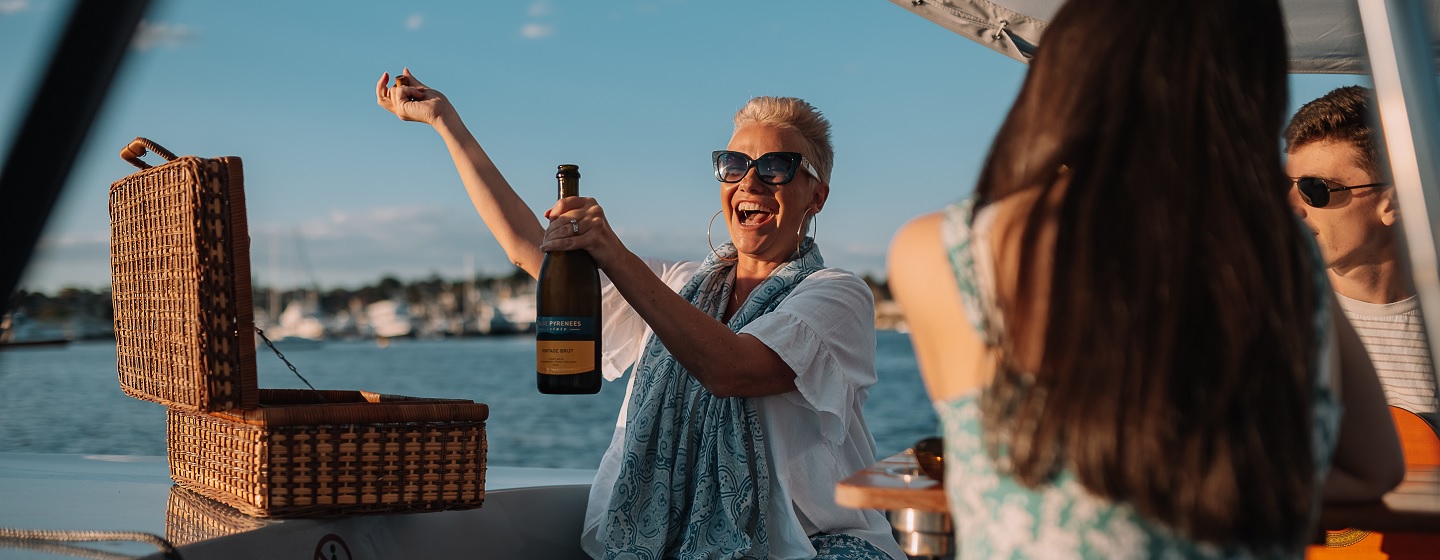 Woman opening bottle of champagne on the boat